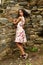 Surprised teenage girl in summer dress by stone wall