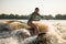 surprised wet woman wakesurfer riding on splashing wave on a warm day