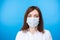 Surprised woman in aseptic mask. light blue background