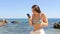 Surprised woman in bikini reading phone content on the beach