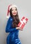 Surprised woman in braces holding Christmas gift. Girl in Santa hat, Xmas or New Year sale concept