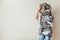 Surprised woman holding metal laundry basket with messy clothes on white background.