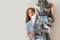 Surprised woman holding metal laundry basket with messy clothes on white background.