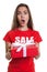 Surprised woman with long brown hair and gift sale in shirt