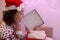 Surprised woman with Santa Claus hat and Christmas sweater opens