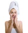 Surprised woman wrapped in a towel applaying cream or moisturiz