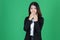 Surprised young Asian business woman closes her mouth with hands on green isolated background