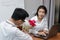 Surprised young Asian woman getting a bouquet of red roses in office on valentine`s day. Love and romance in workplace concept.