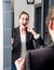 Surprised young beautiful business woman laughing in front of mirror