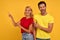 Surprised young couple in red and yellow t-shirts isolated on yellow background studio portrait. People emotions lifestyle concept