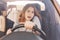 Surprised young cute female driver has telephone conversation via cell phone, drives car, looks with shocked expression as forgets