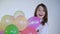 Surprised young girl catches balloons and looks at camera on background