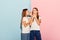 Surprised young girls, two sisters friends in casual style clothes isolated over pink-blue studio background. Fashion