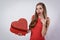 Surprised young woman holding a big heart present valentine\'s day