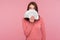 Surprized happy woman with brown hair in pink sweater hiding face behind fan of dollar banknotes, interest-free cash withdrawal