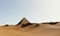 Surreal desert landscape with pyramid.