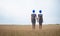 Surreal image of two women standing hand in hand on a field, their heads are replaced by blue balloons