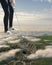 Surreal landscape of Sardinian Nuraghe with young girl playing golf immersed in clouds