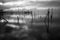 Surreal long exposure view of a lake, with wooden poles on perfectly still water and a pier in the background