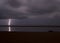 Surreal, stormy night enlightened by thunder on the coastline in