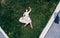 Surrealism. The girl lies on a green lawn in a dress. Aerial view