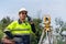 Surveyor Civil Engineer using the phone with equipment theodolite or total positioning station on the construction site