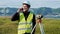 Surveyor man in green work clothes and helmet adjusts the equipment, produces calculations and writes to the notebook on