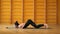 Surya Namaskar. Woman in black bodysuit doing yoga practice in yellow studio on stairs background. Health, lifestyle