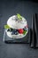 Sushi burger with sesame and berries on dark plate