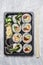 Sushi menu in black transportbox or bento box on gray background, top view, close up