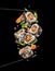 Sushi pieces placed between chopsticks on black background