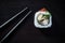 Sushi roll with caviar and chopsticks on black tableboard top view. Japanese food concept.
