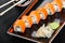 Sushi Roll - Maki Sushi made of salmon, cucumber, avocado and cream cheese on dark wooden background.