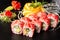 Sushi Rolls with avocado, eel, cucumber and cream cheese inside on black slate isolated. California rolls covered orange tobiko or