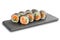 Sushi Rolls with salmon and cucumber wrapped in nori leaf on black slate or stone shale surface isolated on white