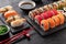 Sushi rolls set, nigiri sushi and soy sauce on a black textured background and chopsticks on the side.