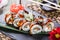 Sushi rolls set with salmon, cream cheese, cucumber, sesame and wasabi on black stone on bamboo mat, selective focus.