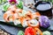 Sushi rolls set with salmon, cream cheese, red caviar, avocado and wasabi on black stone on bamboo mat, selective focus.