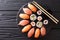 Sushi rolls set served on black stone slate on dark background.