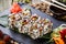 Sushi rolls set with shrimp tempura, cucumber, avocado and sesame on black stone on bamboo mat, selective focus.