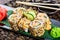 Sushi rolls set with shrimp tempura, cucumber, onion, avocado and sesame on black stone on bamboo mat, selective focus.