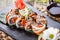 Sushi rolls set with smoked eel, red caviar, sesame and wasabi on black stone on bamboo mat, selective focus.