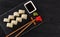 Sushi with salmon on a white plate with wasabi, ginger, soy, chopsticks on a black background