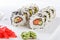 Sushi with salmon on a white plate with wasabi, ginger, soy, chopsticks on a white background
