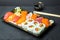 Sushi and Sashimi rolls on a black stone slatter. Fresh made Sushi set with salmon, prawns, wasabi and ginger. Traditional Japanes