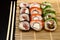 Sushi set with different maki - hosomaki, futomaki and uramaki on bamboo mate with chopsticks