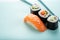 Sushi set with salmon nigiri and roll with cucumber and vegetables with chopsticks on a blue