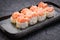 Sushi set served on dark background. Baked maki roll, Philadelphia maki with masago, salmon, cream cheese, avocado and prawn