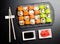 Sushi set served on a stone slate on a dark background. Sushi rolls with salmon, tuna, cucumber, wasabi, soy sauce and ginger.