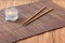 Sushi sticks on brown bamboo food placemat and decorative candle on wooden table